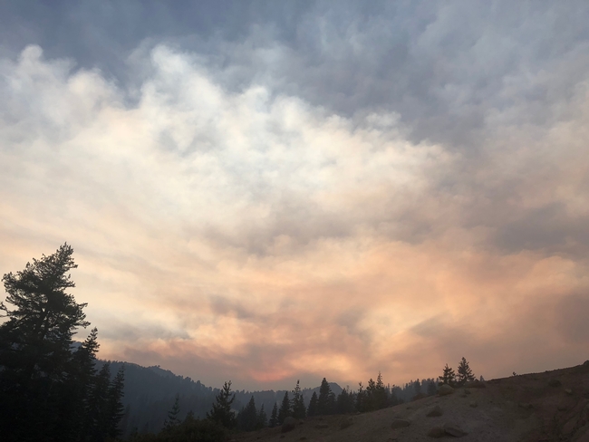 Smoke fills the air above forested mountains