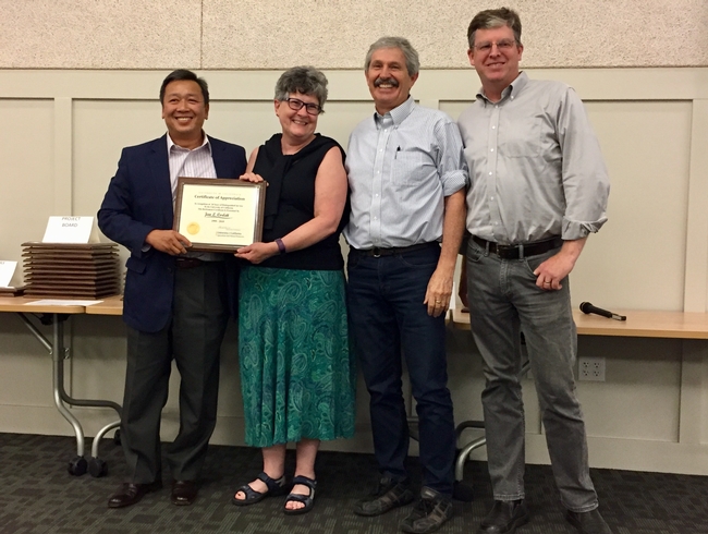 Jan Corlett, second from left, receives thanks and congratulations from Tu Tran, Mark Bell and John Fox.