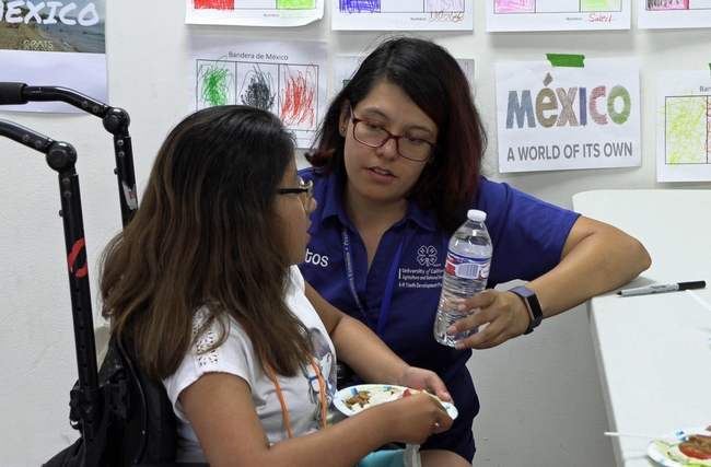 Claudia Diaz Carrasco talks with a student at an event in pre-COVID-19 times.