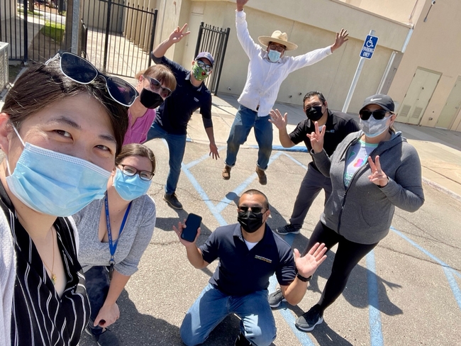 The team members, wearing face masks, pose on a school playground.
