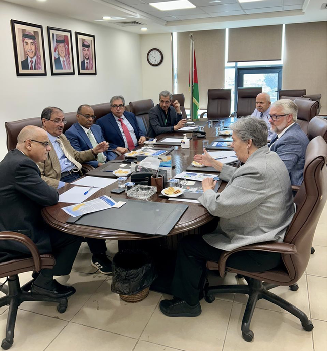 A group of people wearing suits sit around a conference table. Glenda Humiston is speaking