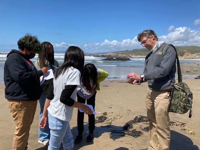 Igor Lacan, asesor de la extensión cooperativa de la UC, a la derecha, describe a los estudiantes de sexto grado algunas de las plantas y animales que viven en el agua de la playa.