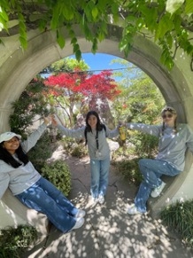 3 youth in a round arch with a pink tree centered in background
