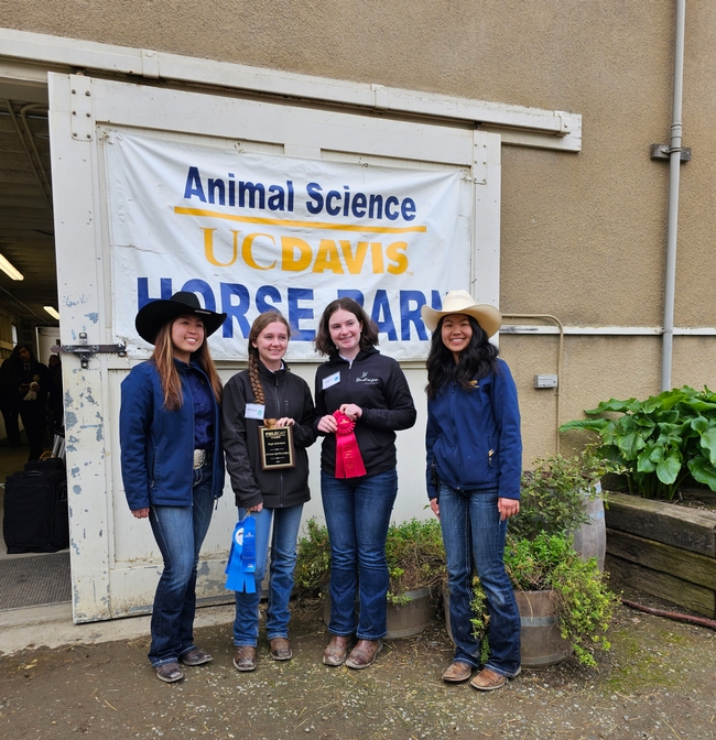 4 youth standing in front of banner reading Animal Science UC Davis Horse Barn. 2 youth in middle hold ribbons and plaque.