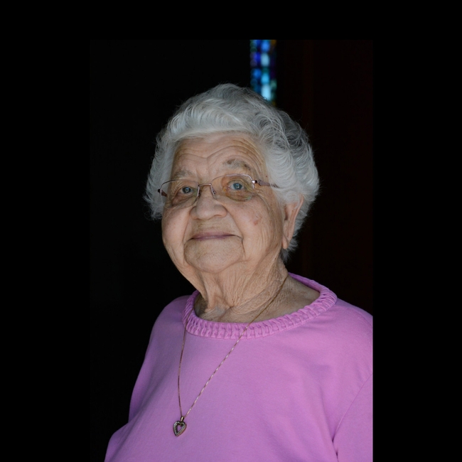 Gray haired older woman in pink top on black background