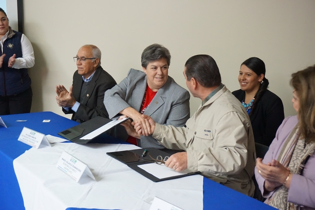 Glenda Humiston, center, and Manuel Vallodolid Seamanduras, right, sign the memorandum of understanding.