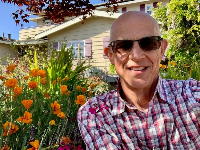 Allen Buchinski shown in his front yard surrounded by orange poppies.