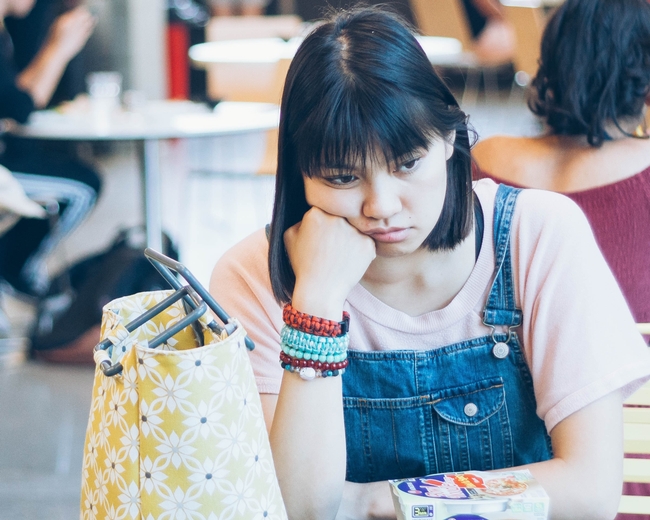 Young woman looks unhappy in a school cafeteria
