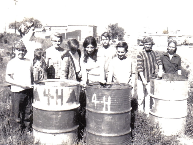 A black-and-white photo showing kids posing with painted trash cans