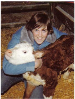 A woman smiles while posing with a calf