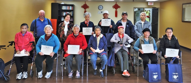 A group of older adults and their instructor pose for a photo celebrating their completion of a six-week workshop series called Eat Healthy, Be Active.