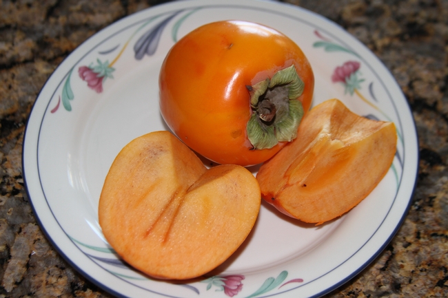 Image of Fuyu persimmon fruit slices on a plate.