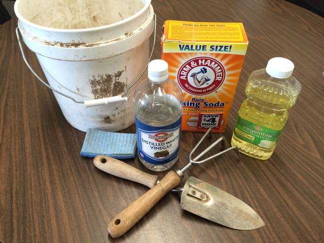 Baking soda, vinegar, vegetable oil, and a scrubber with garden tools.