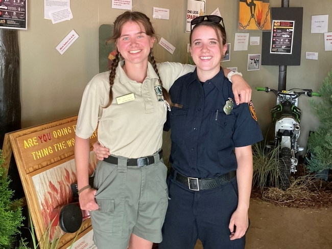 Emily Jackson, in a Forest Service uniform, stands next to her twin sister Lindsay, in her CAL FIRE uniform