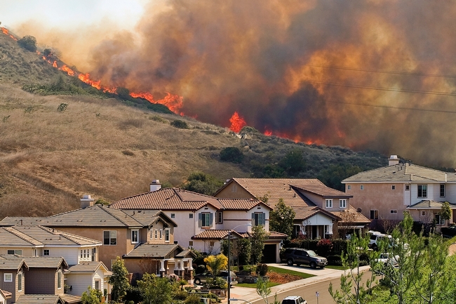 Flames and smoke fill the sky behind a Southern California subdivision.