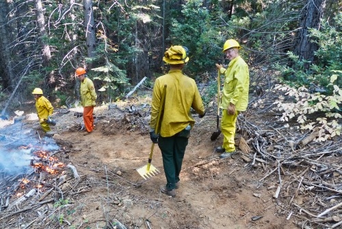 Landowners at a UCCE prescribed fire training are 'holding' the fire on the left side of the fire line that was cut using rakes and other hand tools. The landowner on the far left is firing the burn unit with a drip torch. (Photo: Ames Gilbert)