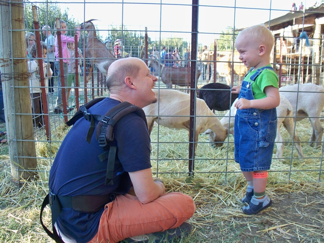 Father and son enjoy a petting zoo on a farm offering agritourism experiences.