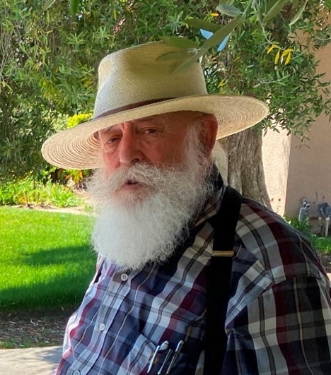 Headshot of Tom Willey wearing a wide-brimmed hat, blue plaid shirt and white beard.