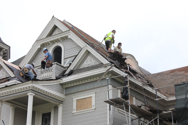 workers on high pitched roof removing over 100 years of roofing material