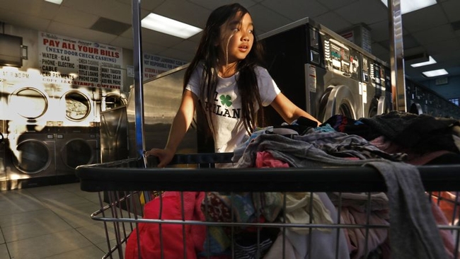 Isabella Kap, 8, helps her grandmother at the laundromat in Long Beach, where members of the large Cambodian community often lend money to one another through informal groups rather than use banks. (Carolyn Cole / Los Angeles Times)
