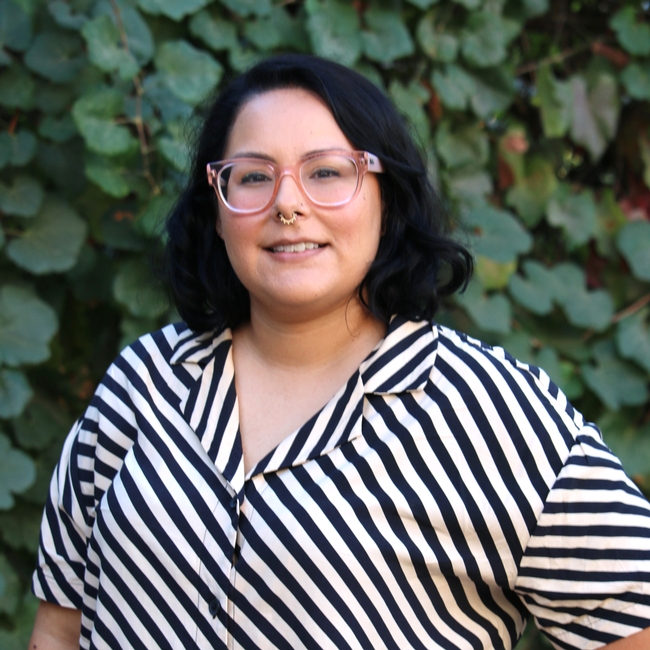 Woman with dark hair and glasses in a striped top