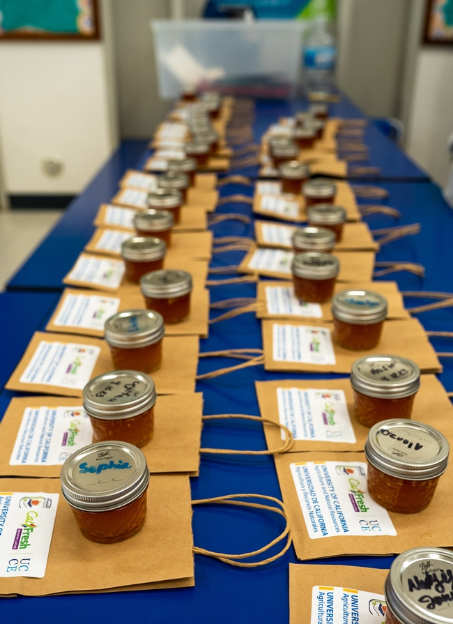 small jars with orange liquid lined up on a long table