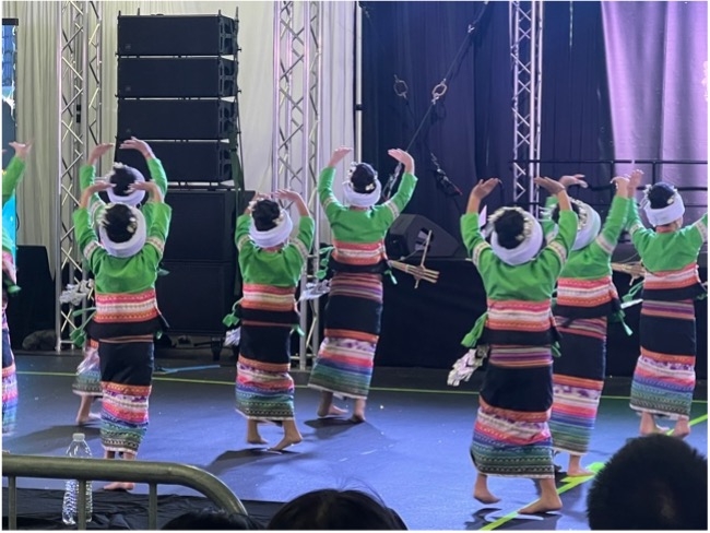 Women dance in traditional Hmong clothing on a stage