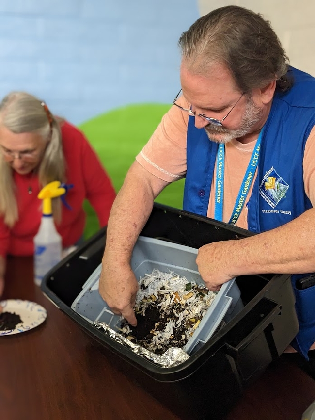 Man with worm bin shows the public how to compost using worms.