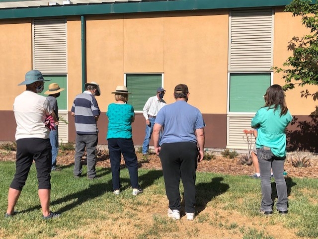 Six people facing an instructor giving a lesson about trees.