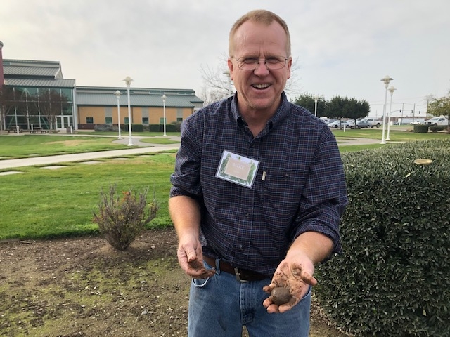 Man holding soil in his hands and smiling.