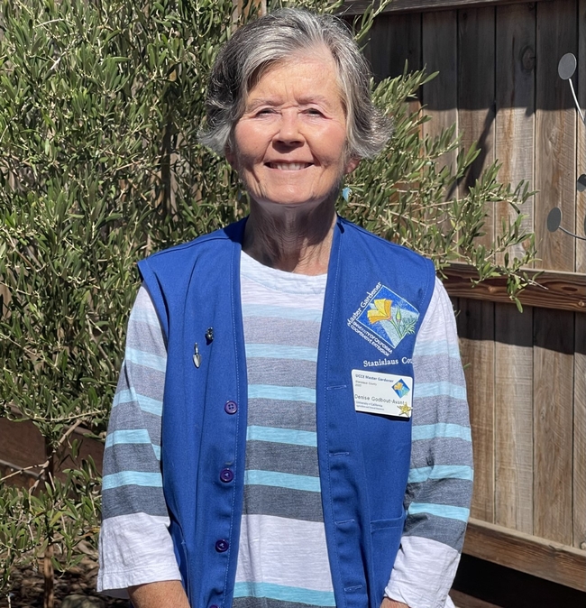 Woman with short, gray hair wearing a blue Master Gardener vest.