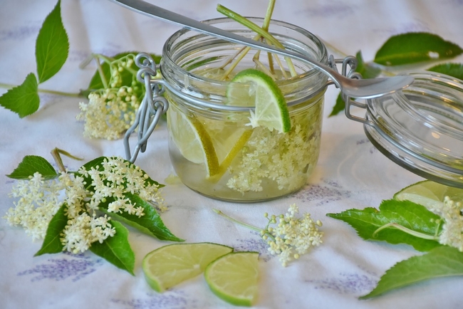 Small mason jar with liquid, lime wedges, and flowers.