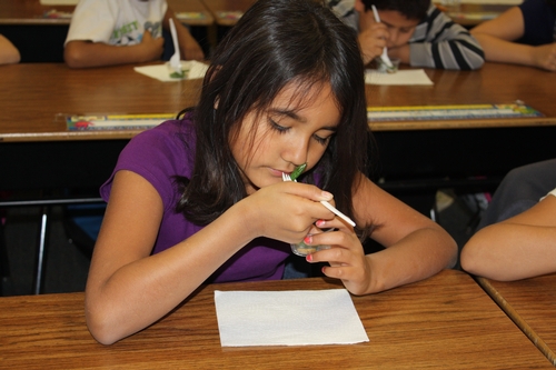 A student using one of her 5 senses to investigate her food.  This SMELLS so good!