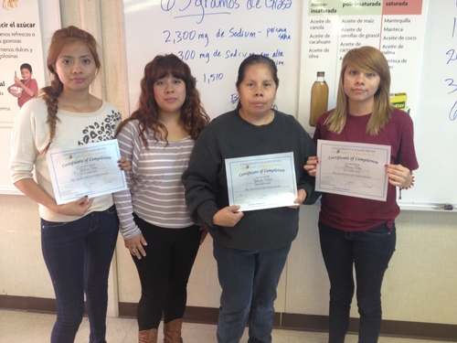 Yolanda V. with her 3 daughters proudly displaying their certificate of completion for Plan, Shop, Save, and Cook nutrition education series