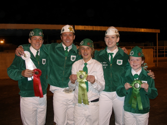 Multiple 4-H youth holding up ribbons and awards.