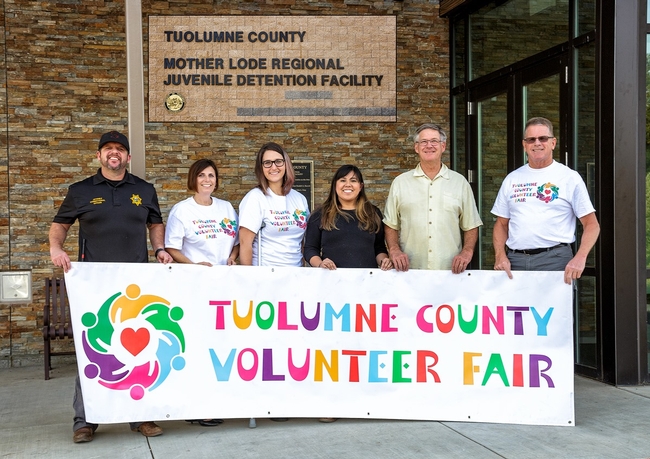 Volunteer Fair staff, Tuolumne County Probation Staff, and local volunteer stand behind Tuolumne County Volunteer Fair banner.