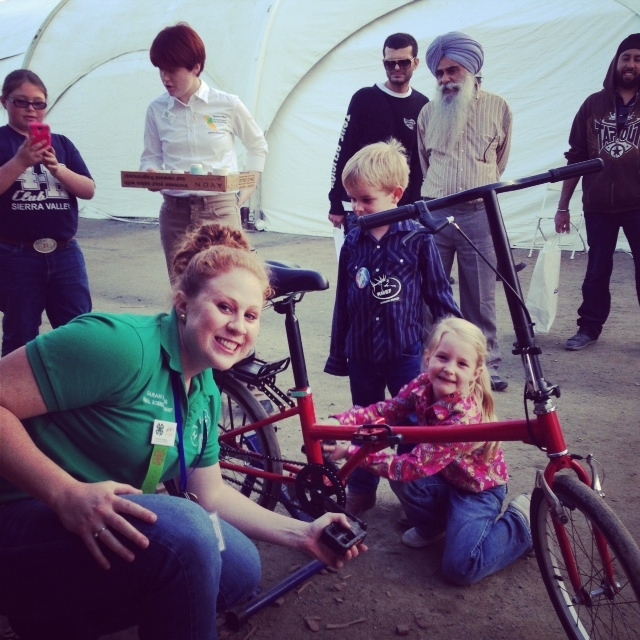 Sarah Watkins de 4-H ayuda a una niña con la bicicleta de batidos.