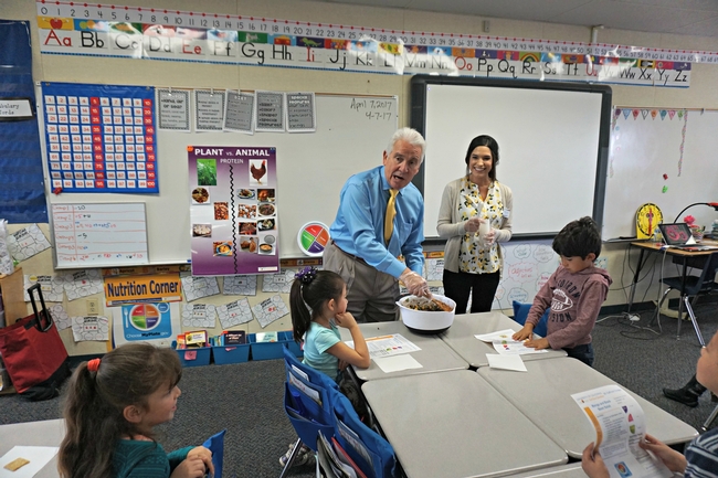 El congresista de EUA Jim Costa mezcla la ensalada para los estudiantes de la primaria La Vina en el condado de Madera County. La educadora de nutrición de UCCE, Angélica Pérez junto al congresista.