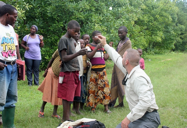 Mark Hoddle comparte algunos insectos con niños que se muestran interesados en una huerta de aguacates en el distrito Rungwe en Tanzania. (Fotografía: Mary Lu Arpaia)