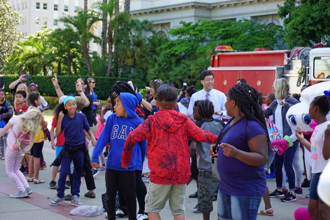 El senador Robert Pan, al centro con camisa blanca, baila con los niños durante el día de campo del programa “Un millón de comidas de verano.”