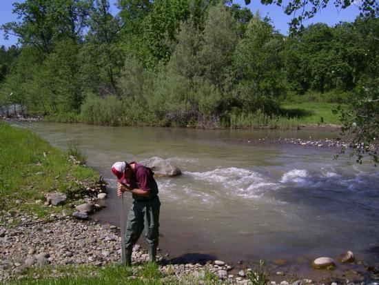 Larry Forero checks water transparency of Cow Creek. Photo by Lisa Thompson.