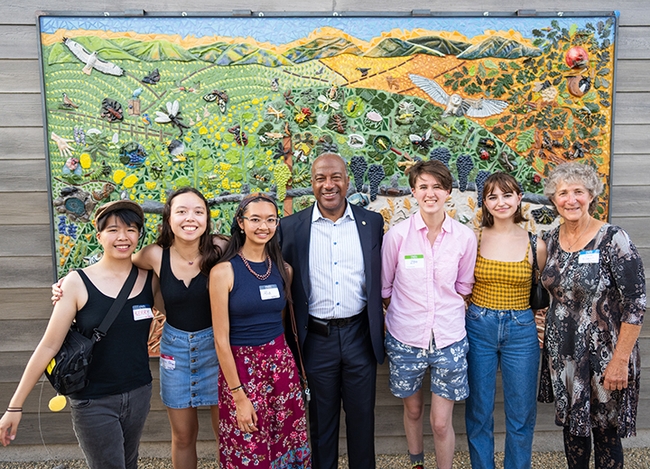 Posing for a celebratory photo are five mural participants with Chancellor Gary May and UC Davis distinguished professor Diane Ullman. From left are Kerry Lin, Sierra Deaver, Alia Tu, Chancellor May, Zoe Meilandt, Lily Nugent and Professor Ullman. (Photo courtesy of Jael Mackendorf, UC Davis College of Agricultural and Environmental Sciences)