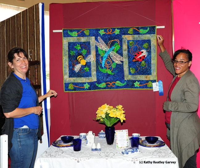 Gloria Gonzalez (left) of Vallejo, superintendent of McCormack Hall, Solano County Fair, and assistant Iris Mayhew of Vallejo hang a quilt by LaQuita Tummings of Vallejo. (Photo by Kathy Keatley Garvey)