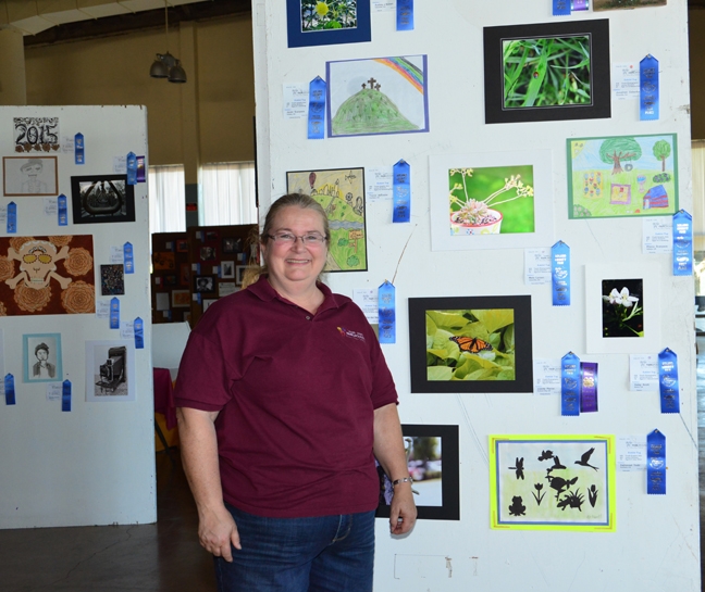 McCormack Hall assistant superintendent Sharon Payne of Vallejo, a past president of the Solano County 4-H Leaders' Council, stands next to youth photography featuring insects. (Photo by Kathy Keatley Garvey)