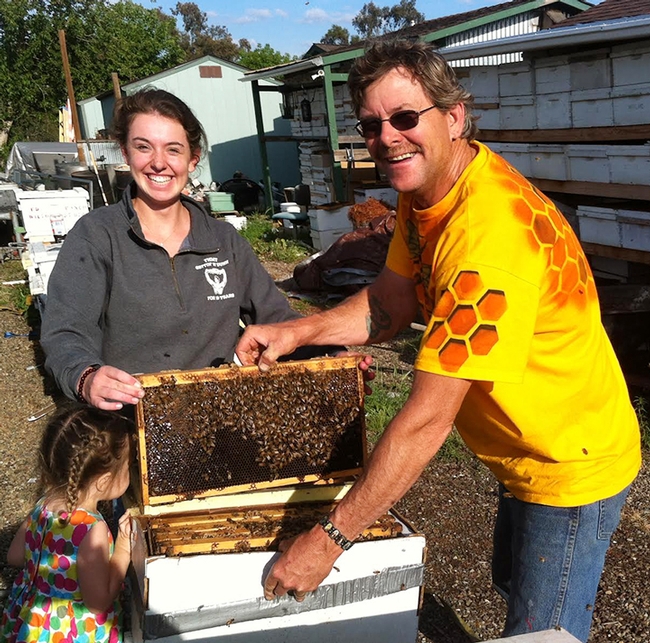 Beekeeper Brian Fishback helping Sheridan Miller with her hive. (Photo by Craig Miller)