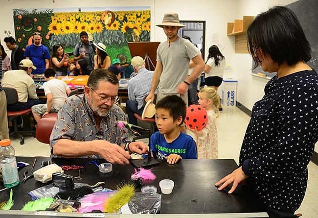 While mom (right) observes, Steven Mao, 7, of Davis, watches Dave Driscoll of the Fly Fishers of Davis tie a fly during the 104th annual UC Davis Picnic Day. (Photo by Kathy Keatley Garvey)