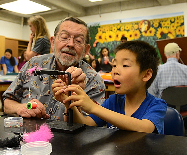 Steven Mao is totally fascinated with Dave Driscoll's fly-tying demonstration. An avid angler, Driscoll retired in 2004 as a Solano County deputy district attorney. (Photo by Kathy Keatley Garvey)