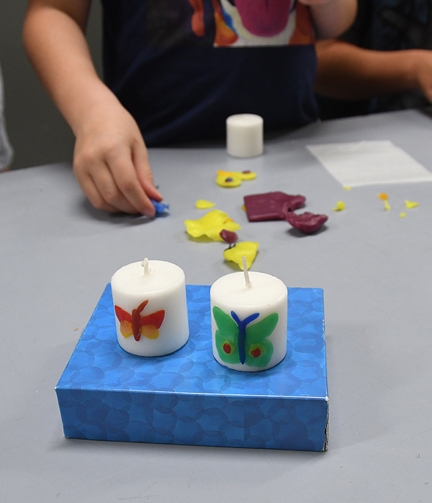 The family craft activity involved inserting moth/butterfly replicas on wax candles. (Photo by Kathy Keatley Garvey)