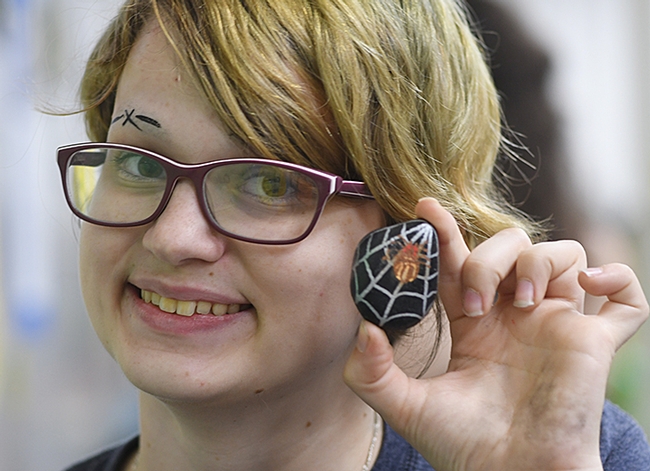 Isabelle Gilchrist, a second-year entomology major who staffed the family crafts activity table, displays a paint rock she created. (Photo by Kathy Keatley Garvey)