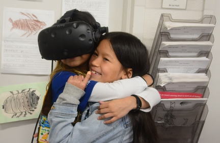 Brownie Girl Scout Jayda Navarette (left), 8, of Vacaville, is comforted by Keira Yu, 8, of Vacaville as the spiders come into view in a virtual reality demonstration at the Bohart Museum of Entomology. (Photo by Kathy Keatley Garvey)